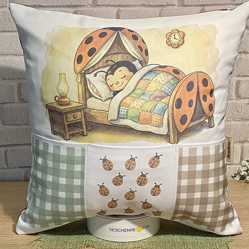 Kissen mit Taschen für Geschenke und einem Bild eines Marienkäfers in einem Kinderbett